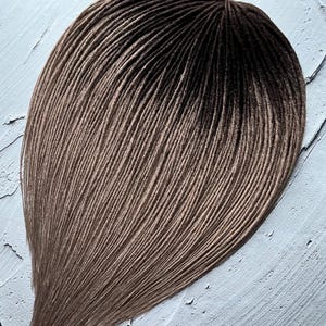 May include: A set of brown and blonde ombre synthetic dreadlocks. The dreadlocks are arranged in a fan shape and are ready to be installed.
