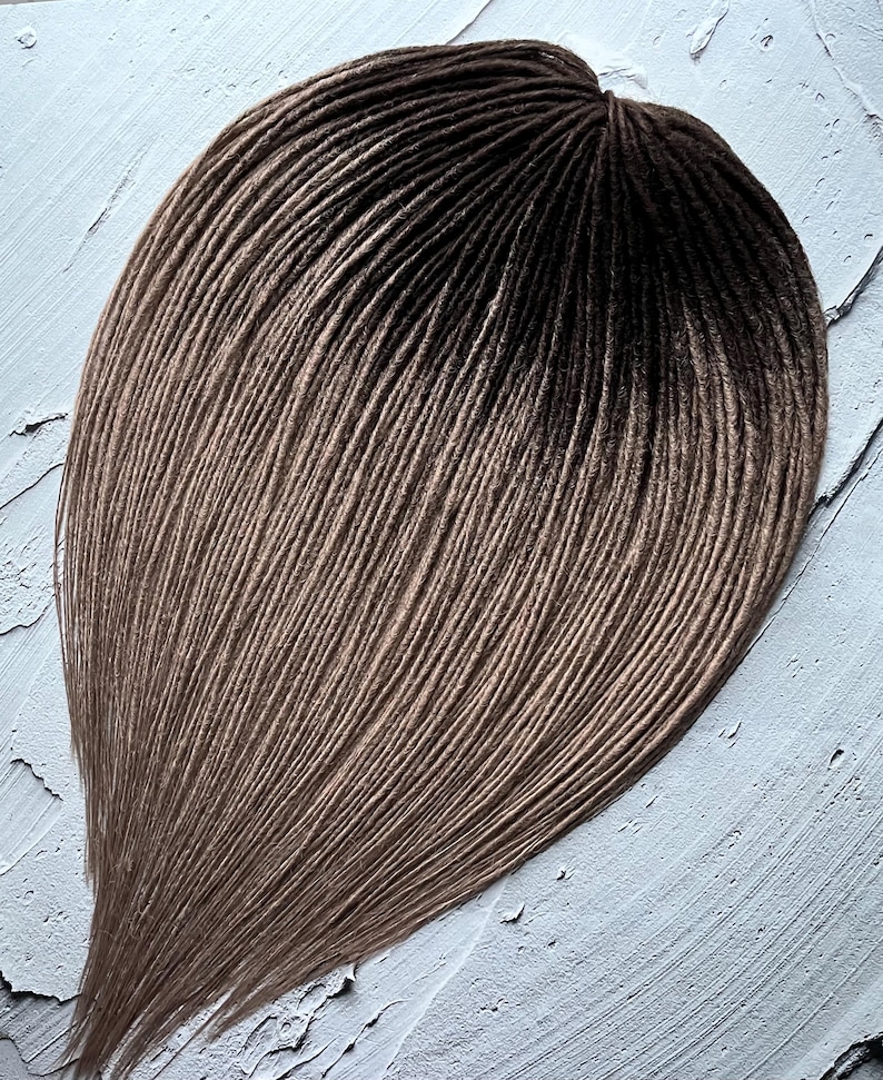 May include: A set of brown and blonde ombre synthetic dreadlocks. The dreadlocks are arranged in a fan shape and are ready to be installed.