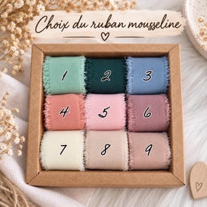 May include: A square cardboard box containing nine rolls of frayed-edge chiffon ribbon arranged in a grid. Each roll is labeled with a number from one to nine, featuring colors including mint, dark green, blue, peach, pink, mauve, cream, and beige.