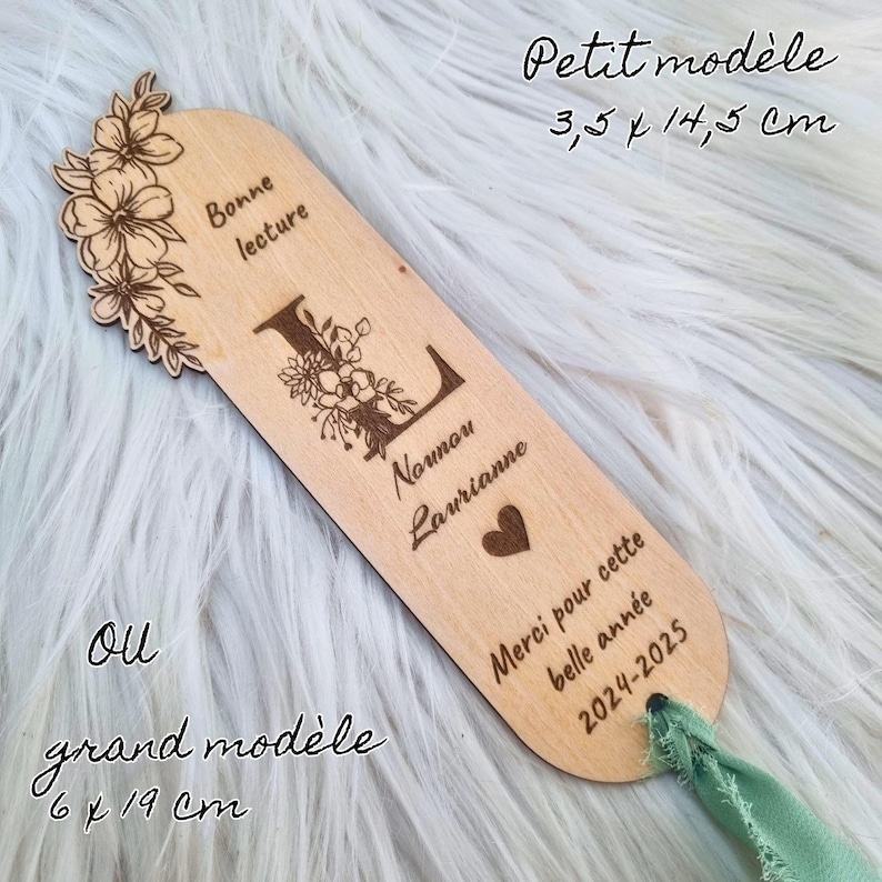 May include: A wooden bookmark with floral and initial letter engraving. The bookmark has the text "Bonne lecture", "Nounou Laurianne", "Merci pour cette belle ann&eacute;e 2024-2025". The bookmark measures 3.5 x 14.5 cm.