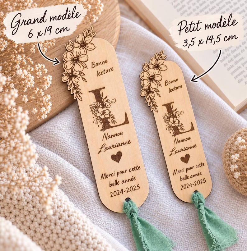May include: Two light-colored wooden bookmarks with rounded ends and sage green fabric tassels. Each features a floral design, the letter L, the text Bonne lecture, Nannou Laurianne, a heart, Merci pour cette belle ann&eacute;e, and 2024-2025.