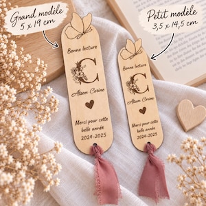May include: Two light-colored wooden bookmarks with rounded tops, each featuring an engraved butterfly, a floral letter C, the text "Bonne lecture," "Atsem Corine," a heart, and "Merci pour cette belle ann&eacute;e 2024-2025." Each has a dusty pink fabric tassel.