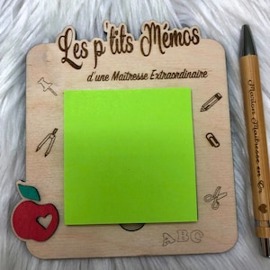 Peut inclure: Un tableau d'affichage en bois avec un post-it vert, une pomme rouge avec un cœur et le texte "Les p'tits Memos d'une Maitresse Extraordinaire" et "ABC".