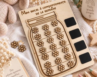 May include: A light-colored wooden board featuring a jar illustration with the text "MON BOCAL À COMPORTEMENTS DE LA SEMAINE" and twenty-two small wooden flower-shaped tokens. Four black rectangular spaces are positioned on the right side.