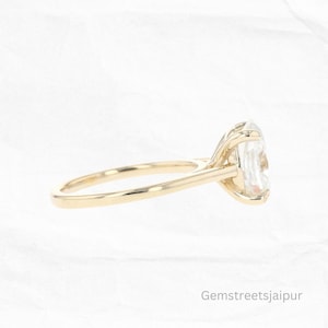 May include: A gold engagement ring with a large oval-shaped diamond. The ring is set on a simple band and has a delicate, prong setting.