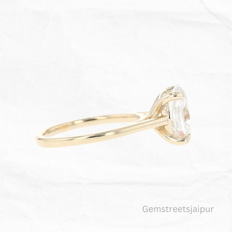 May include: A gold engagement ring with a large oval-shaped diamond. The ring is set on a simple band and has a delicate, prong setting.