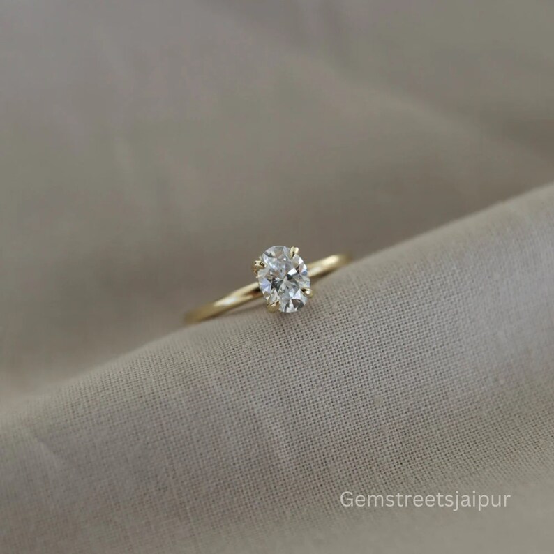 May include: A gold band ring with a single oval-shaped diamond.