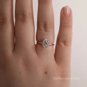 May include: A rose gold engagement ring with a large oval-shaped diamond.