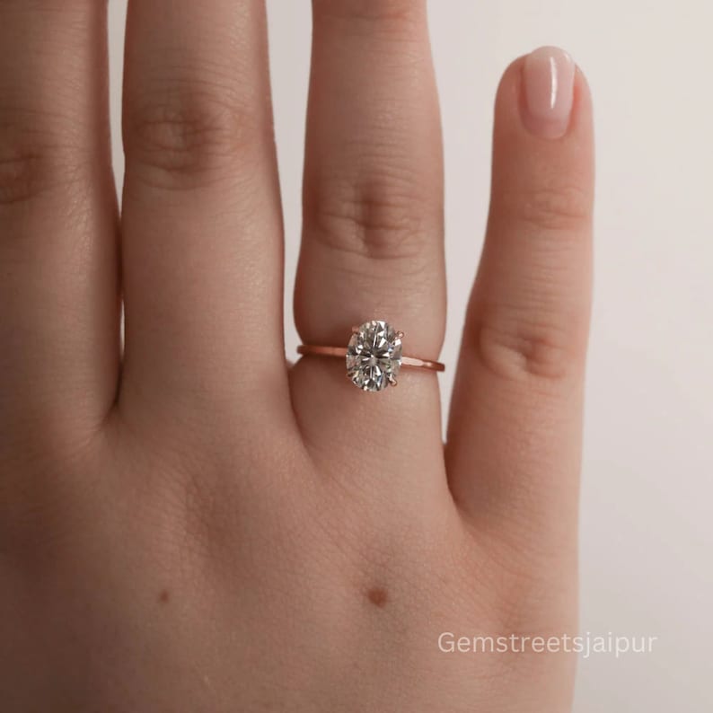May include: A rose gold engagement ring with a large oval-shaped diamond.