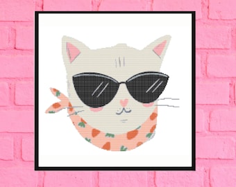 May include: A white cat wearing black sunglasses and a pink and orange scarf with green leaves. The cat has a pink nose and a pink heart on its chest.