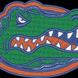 以下が含まれることがあります： 緑色のアリゲーターの頭部が刺繍されたパッチ。白い歯とオレンジ色の口が特徴です。アリゲーターは青とオレンジで縁取られ、青い縁取りがあります。衣類やアクセサリーに最適です。