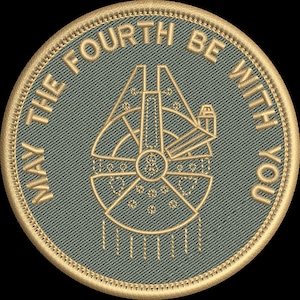 May include: Embroidered patch with a gold border and a teal background. The patch features a gold image of the Millennium Falcon and the text "MAY THE FOURTH BE WITH YOU" in gold lettering. The patch is round.