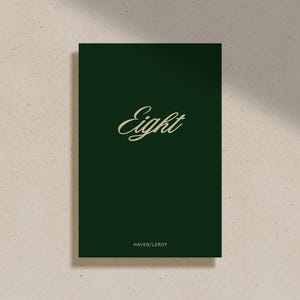 以下が含まれることがあります： 暗い緑色のカードに、金色の筆記体で「Eight」と書かれています。カードの下部には、より小さな金色のフォントで「HAVEN LEROY」と印刷されています。