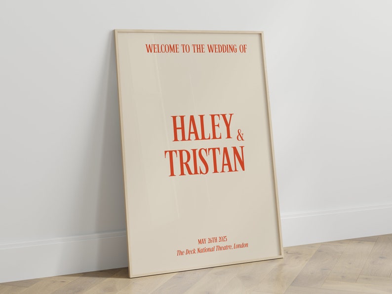 May include: A beige wedding announcement poster with a wooden frame. The text reads "Welcome to the wedding of Haley & Tristan, May 26th 2025, The Deck National Theatre, London."