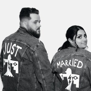 May include: A black and white photograph of a couple wearing denim jackets with the words "Just Married" written on the back. The jackets feature a stylised bird design.