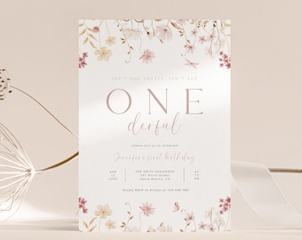 May include: A floral-themed invitation for a first birthday celebration. The invitation features the words "ONE derful" in a soft pink hue, with additional text detailing the event's date, time, and location. Delicate floral illustrations adorn the top and bottom edges.
