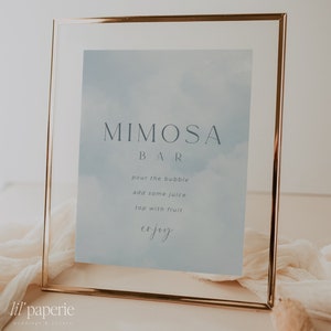 May include: A gold-framed sign with a blue watercolor background and the text "MIMOSA BAR" in gray. The sign also includes instructions for making a mimosa: "pour the bubble, add some juice, top with fruit, enjoy".