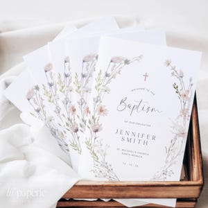Peut inclure: Un ensemble de cartes de programme de baptême blanches avec un motif floral aquarelle dans des tons de rose, violet et vert. Le texte indique "Bienvenue au baptême de notre fille Jennifer Smith, Église Saint-Michel, Santa Monica, 15 10 2x".