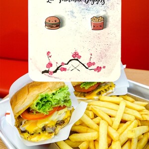 May include: A pair of food-themed earrings featuring a burger and fries with smiling faces, set against a floral background. The earrings are on a card with the text "Lil' Samurai Designs". A burger and fries are also shown in the image.