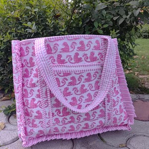 May include: A pink and white tote bag with a pink monkey print and white stripes. The bag has a ruffled edge and two pink straps.