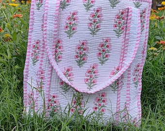 May include: A white cotton tote bag with pink and green floral print and pink and white striped trim. The bag has two handles.
