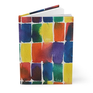May include: A colorful notebook with a watercolor design of rectangular blocks in shades of red, orange, yellow, green, blue, and purple.