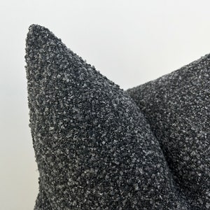 May include: Two black triangular cushions with a textured surface. The cushions are made of a material that resembles small pebbles.