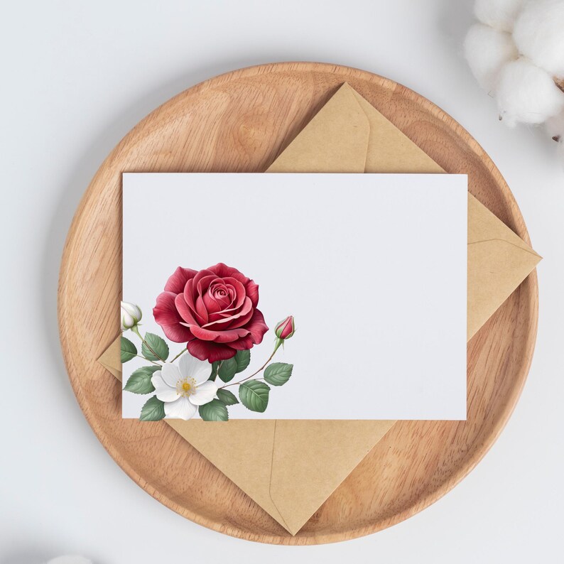 May include: A white card with a watercolor design of a red rose and white flowers, with green leaves and buds. The card is on a wooden tray with a brown envelope.
