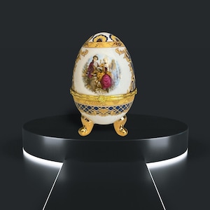 May include: A white porcelain egg-shaped trinket box with gold accents and a blue and gold patterned base. The lid features a painted scene of two people in a garden setting.