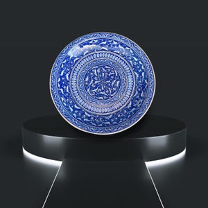 May include: A blue and white ceramic plate with a decorative design of stylized birds and flowers. The plate has a raised rim and a glossy finish.