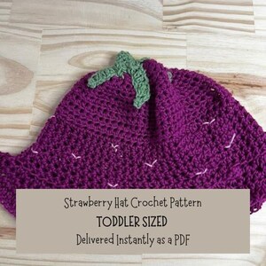 May include: A purple crocheted strawberry hat with green leaves. The hat is toddler sized and the pattern is available as a PDF download. "Strawberry Hat Crochet Pattern TODDLER SIZED Delivered Instantly as a PDF"
