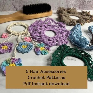 Puede incluir: Una colección de accesorios para el cabello hechos a mano con ganchillo en varios colores, incluyendo morado, azul y verde. La imagen presenta varias coleteros y adornos florales, junto con un cepillo para el pelo de madera. El texto en la imagen dice: "5 Hair Accessories Crochet Patterns Pdf Instant download."