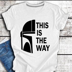 May include: White t-shirt featuring a black Mandalorian helmet graphic and the text "This is the way".