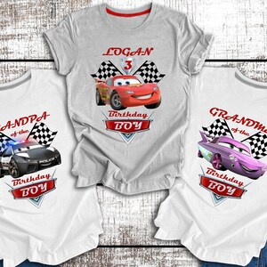 Pu&ograve; includere: Tre magliette bianche a tema Cars. Le magliette presentano un'auto da corsa rossa, un'auto della polizia nera e un'auto rosa. Ogni maglietta ha un design a bandiera a scacchi e il testo "Birthday Boy". Una maglietta ha il nome "Logan" e il numero "3".