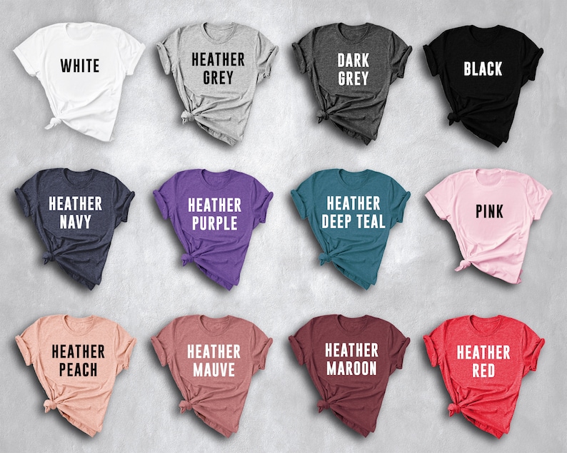 May include: Twelve t-shirts in a variety of colours, including white, grey, black, navy, purple, teal, pink, peach, mauve, maroon, and red. Each shirt has a different colour and a text label indicating the colour.