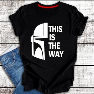 May include: Black t-shirt with a white graphic of a Mandalorian helmet and the text "This is the way".