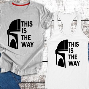 May include: Two shirts featuring a black and white graphic of a Mandalorian helmet and the text "This is the way". One shirt is a grey t-shirt and the other is a white tank top.