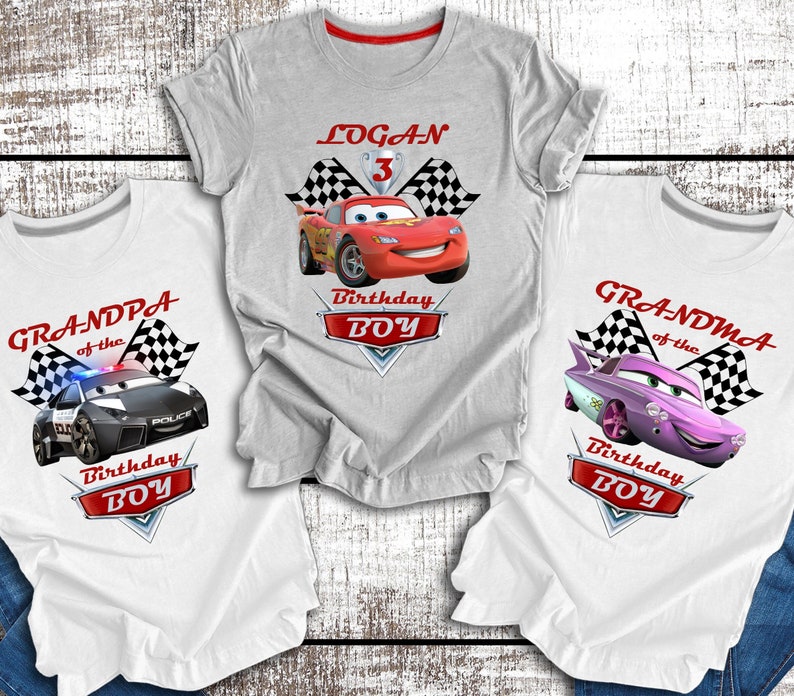 Pu&ograve; includere: Tre magliette bianche a tema Cars. Le magliette presentano un'auto da corsa rossa, un'auto della polizia nera e un'auto rosa. Ogni maglietta ha un design a bandiera a scacchi e il testo "Birthday Boy". Una maglietta ha il nome "Logan" e il numero "3".