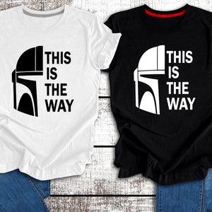 May include: Two t-shirts featuring a black and white image of a Mandalorian helmet and the text "This is the way". One t-shirt is white with black text and the other is black with white text.