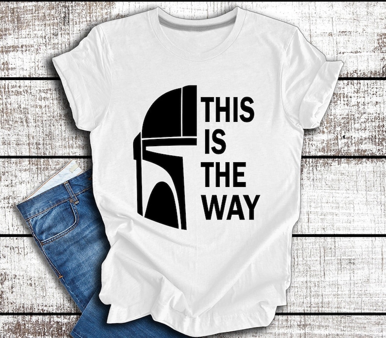 May include: White t-shirt featuring a black Mandalorian helmet graphic and the text "This is the way".