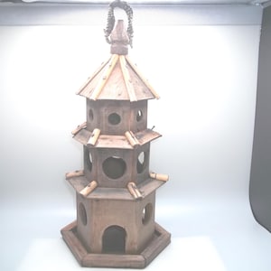 May include: A wooden birdhouse shaped like a pagoda with multiple levels and openings. The birdhouse is painted brown and has a decorative top.