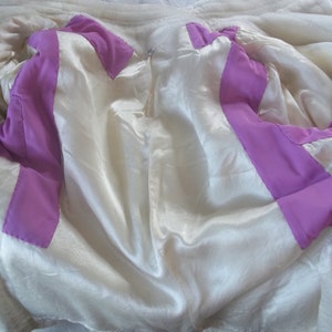 Puede incluir: El interior de una chaqueta blanca con un forro morado. El forro es visible a trav&eacute;s de la chaqueta abierta.