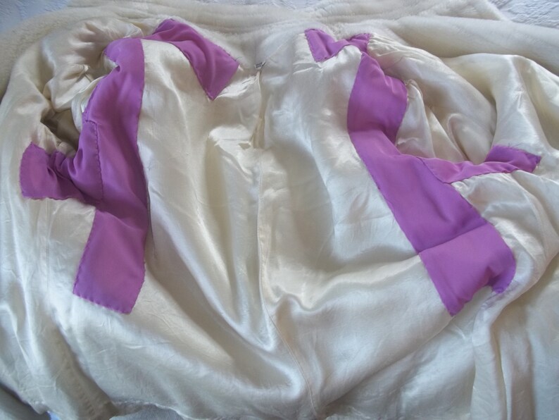 Puede incluir: El interior de una chaqueta blanca con un forro morado. El forro es visible a trav&eacute;s de la chaqueta abierta.