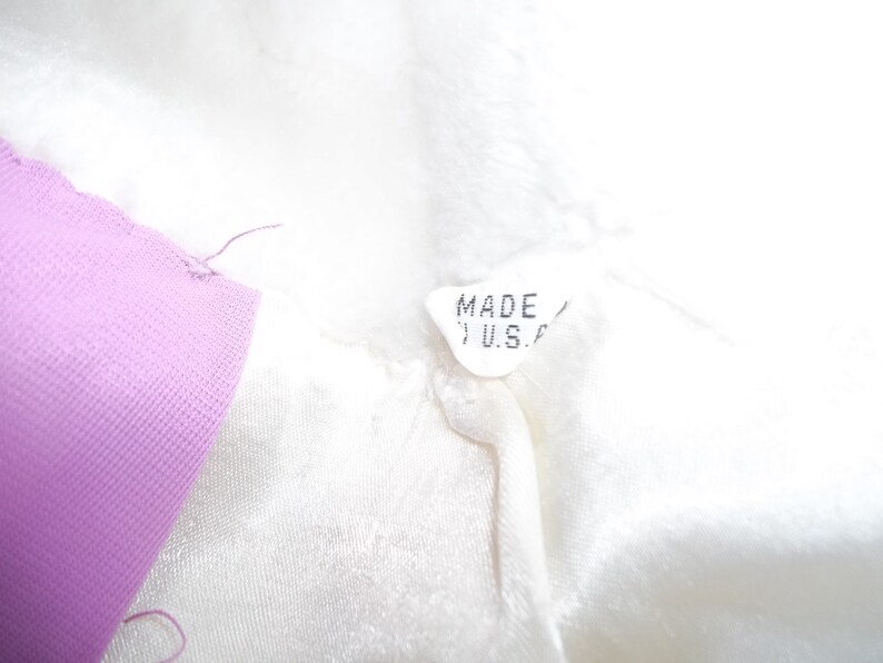 Puede incluir: Una etiqueta de tela blanca con el texto "MADE IN U.S.A." impreso en ella. La etiqueta est&aacute; unida a una prenda blanca.