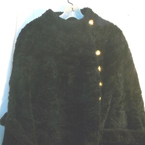 May include: A dark green fuzzy cardigan with gold buttons. The cardigan has a high collar and long sleeves.