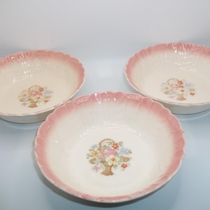 May include: Three white ceramic bowls with pink rims. Each bowl features a floral design with a basket of flowers.