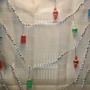 May include: A silver chain with colorful glass ornaments. The ornaments are shaped like teardrops and have a variety of colors, including red, green, blue, and orange.