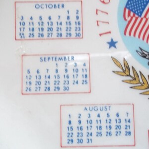 May include: White decorative item with calendar months of August, September, and October. The design includes the American flag and the text "1776" and "200 YEARS". The calendar dates are in blue.