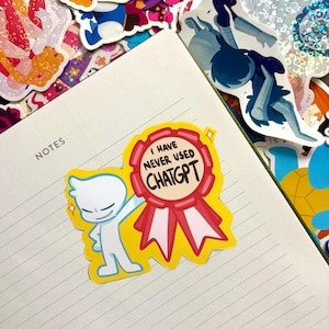 May include: A die-cut sticker featuring a white cartoon character standing next to a red and white award ribbon. The ribbon contains the black text I HAVE NEVER USED CHATGPT. The sticker is placed on a lined notebook page with other stickers.