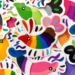 May include: A collection of die-cut stickers featuring stylised shrimp illustrations. Each shrimp displays vibrant rainbow stripes, solid colour blocks, and whimsical patterns in shades of pink, green, blue, orange, and purple with star-shaped eyes.